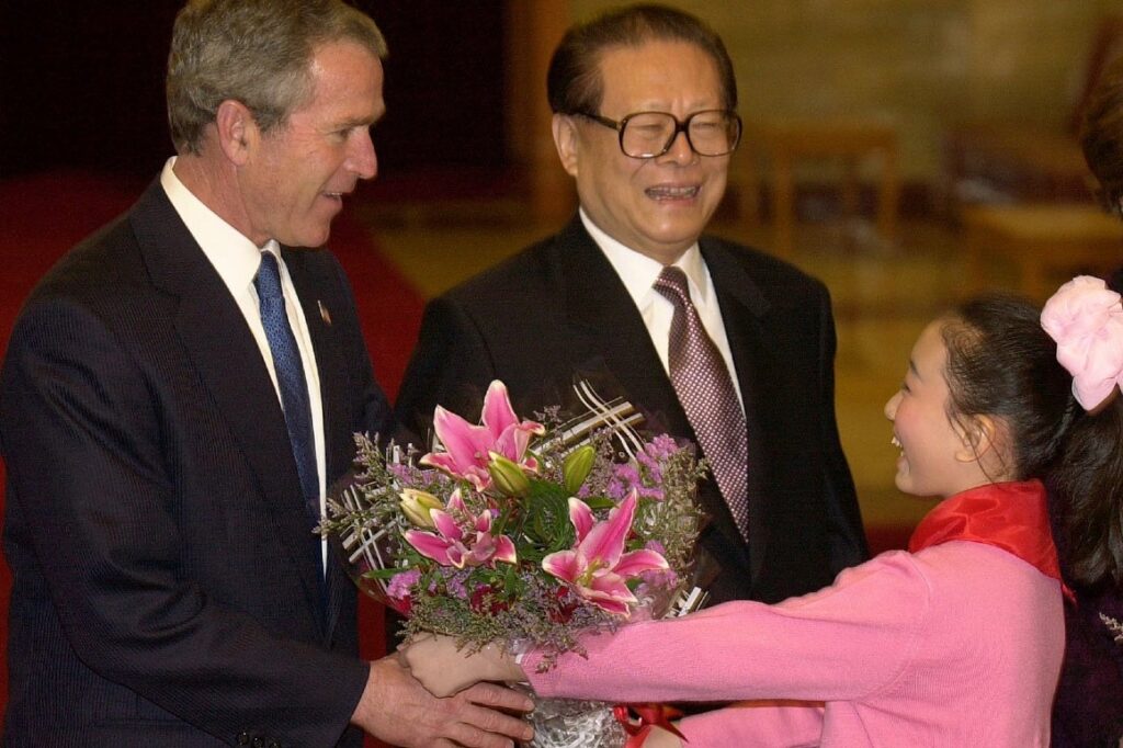Former President George W. Bush  is given flowers by an unidentified girl as former Chinese President Jiang Zemin greets him upon arrival in 2002.